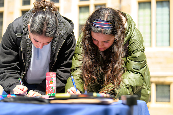 Two students lean over a table as they sign at First Fellows’ signing day.